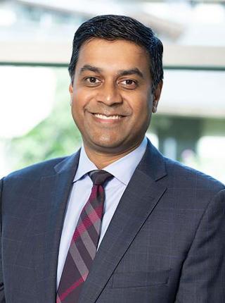 Jay Simhan, a male urologist, wearing a suit and smiling